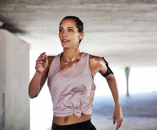 Fotografie Running, fitness and woman with music for cardio exercise in underground, health or wellness