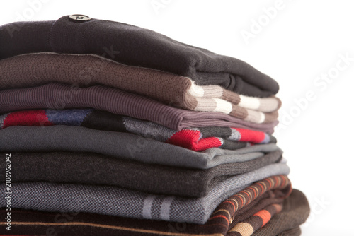 Fotografía Close up shot of stack of neatly folded men sweaters and cardigans showing top button detail on white background