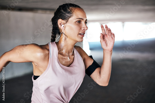 Fotografie Running, exercise and woman with earphones for cardio training with sweat, body health or wellness