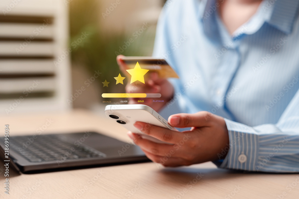 Obraz premium Customer loyalty program membership reward and premium status upgrade. Woman hands holding smartphone and credit payment for online shopping.