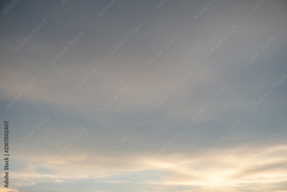 Obraz premium Sunset sky with warm golden light breaking through soft grey clouds backdrop