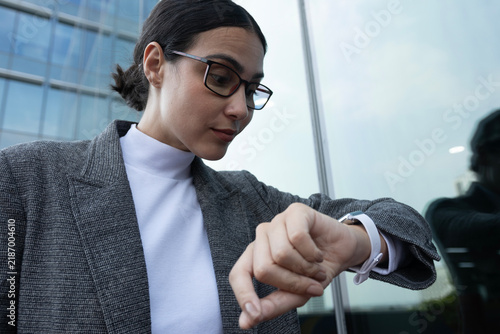 Fotografie Horizontal close-up of a Latina businesswoman anxiously checking the time on her wristwatch