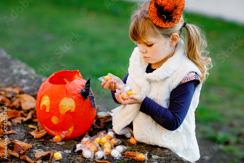 Fotografie Little toddler girl dressed as a witch trick or treating on Halloween