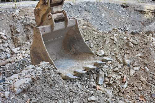 Foto Heavy excavator bucket with teeth resting on excavated soil and gravel at an urb
