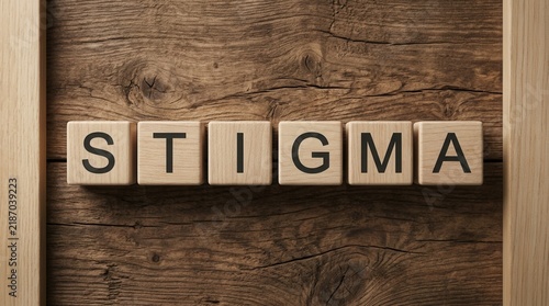 The word stigma spelled out with wooden blocks on a rustic wooden background with shapes.