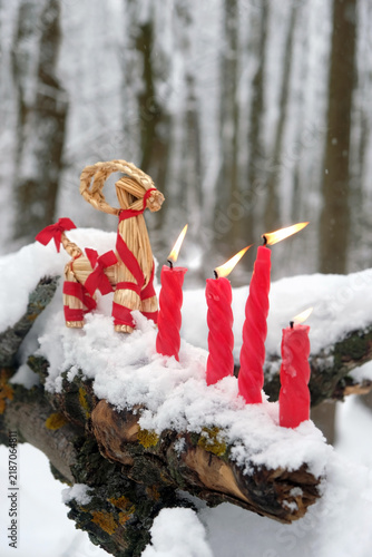 Canvastavla straw Yule Goat and burn red candles on snowy tree in winter forest