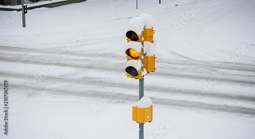 A yellow traffic light showing a caution signal during a heavy winter snowstorm