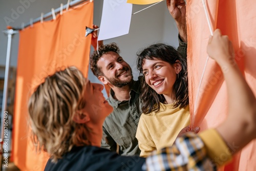 Friends hanging photos on string in colorful indoor photo booth
