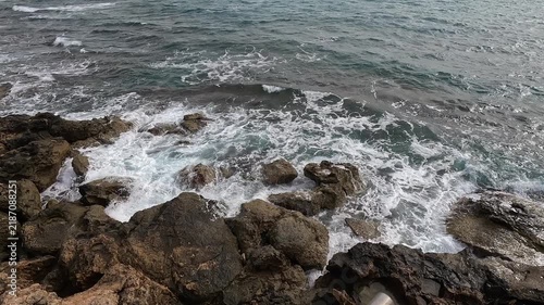 Gentle waves breaking over rocky Mediterranean coastline in Paphos, Cyprus