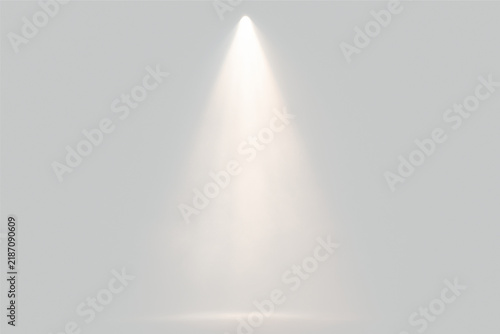 A single warm spotlight shines downward onto a dark, smoky stage. The beam of light highlights the texture of the mist and creates a soft illuminated area on the floor beneath it.
