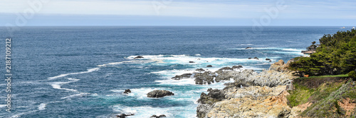 Canvas Print Wide panoramic Pacific coastal landscape with blue ocean, turquoise breaking surf and a rugged rocky shoreline framed by coastal vegetation