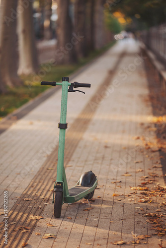 Quiet afternoon stroll along a park path with a green scooter resting on the pavement