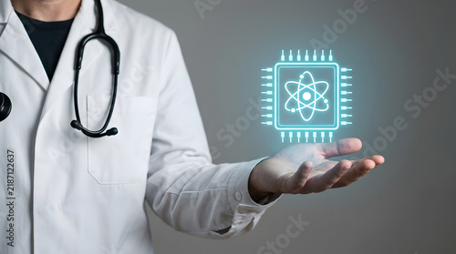 Doctor holding glowing hologram of microchip with atom symbol representing nanotechnology medicine