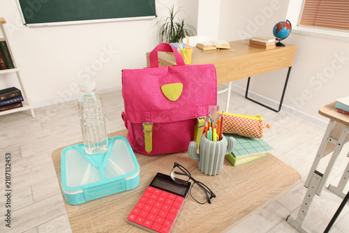 Back to school preparation, student supplies and backpack on desk in classroo...