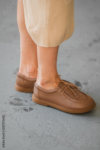 Obraz na plátně Beige knit dress hem drapes over leg, brown leather loafers ensemble, standing o