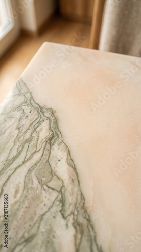 Close-up view of a polished marble surface with intricate green veining and creamy texture.