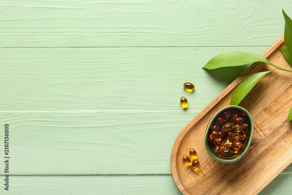 Obraz premium Wellness and natural supplements, omega 3 fish oil capsules in bowl with green leaves on wooden tray for healthy lifestyle and holistic medicine