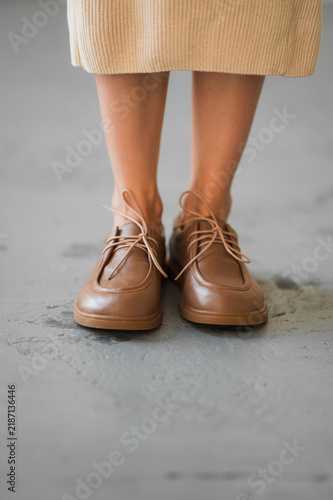 Obraz na plátně Beige knit dress hem with tan leather oxford shoes visible on neutral concrete f