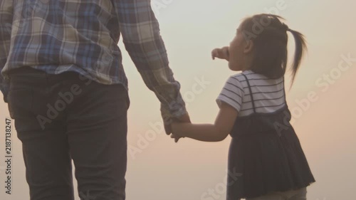 Tender moment between daughter and father, little girl holds and plays her father’s hands and pointing out the scenery.