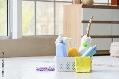 Basket with cleaning supplies on floor in living room