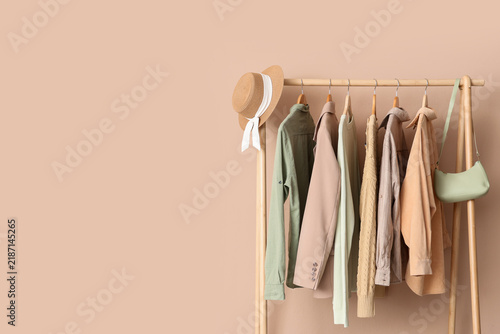 Sustainable fashion and capsule wardrobe, clothes hanging on a wooden rack with a straw hat and handbag in a minimalist interior