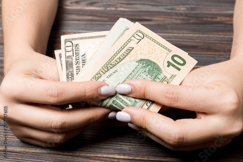 Cuadro en lienzo Perspective view of ten dollar banknotes in female hands on wooden background