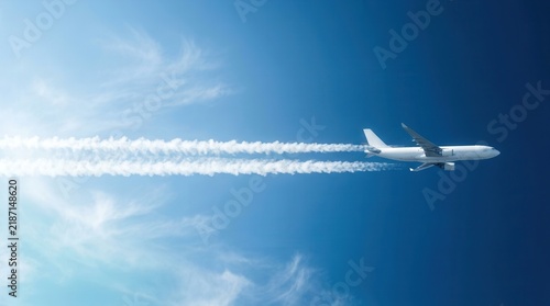 Cargo plane generating long white contrails across a clear blue sky