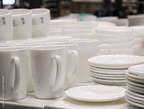 Fotografie White ceramic cups with saucers arranged in neat stacks on retail store shelving