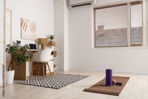 Workplace and sports equipment on mat in interior of living room