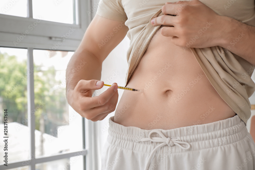 Obraz premium Diabetic young man giving himself insulin injection at home, closeup