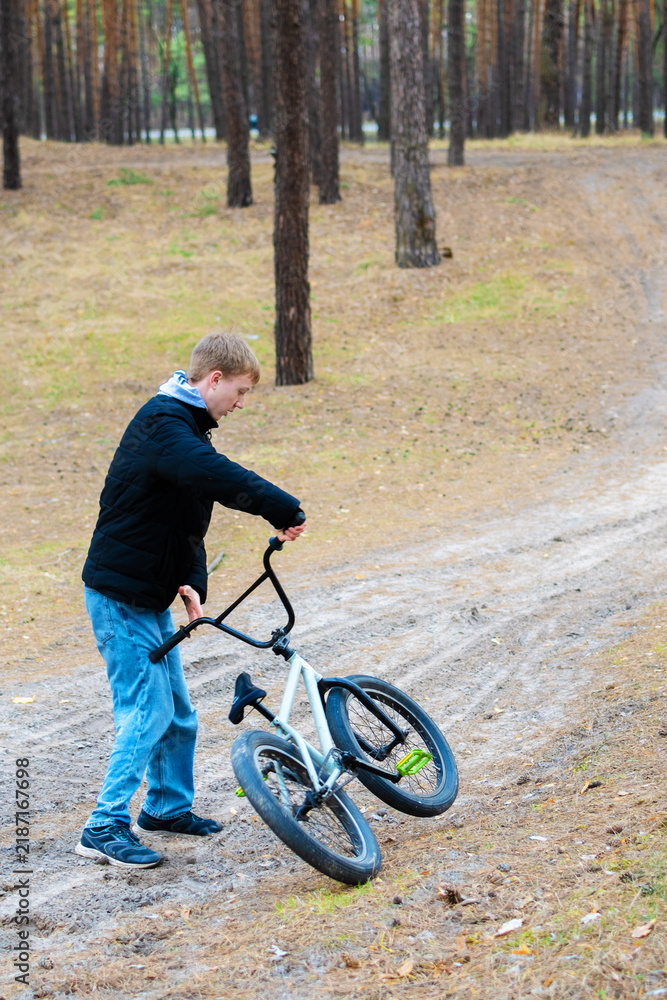 Fototapeta premium Young man riding a bmx bike on a dirt path in a pine forest outdoor recreation