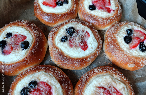 Yeast-dough vatrushki with cottage cheese, berries, and streusel on a baking sheet. Traditional Russian pastry. Close-up. Top view