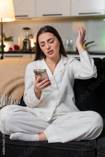 Bild auf Leinwand Young woman scrolls smartphone at night home sees lose alert from online game or lottery feels upset
