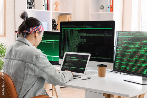 Female programmer working with laptop at desk in office