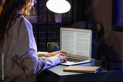 Female writer editing text on laptop before publishing in office at night