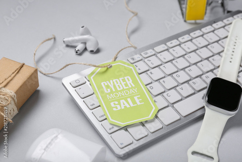 Tag with text CYBER MONDAY SALE and gadgets on light background, closeup