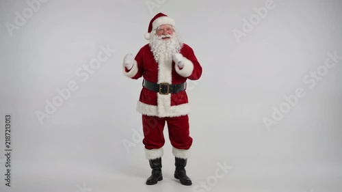 Full length of Santa Claus standing against white background, traditional saint nicholas in red suit and boots talking and gesturing cheerfully, christmas holiday character studio video clip