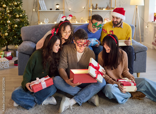 Obraz na płótnie Christmas friends open gifts with joyful laughter