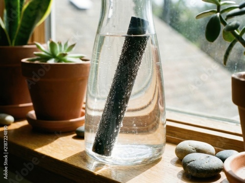 Bamboo charcoal water filter stick purifying water in a glass carafe at home