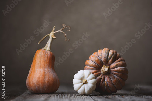 Decorative gourd and pear squash arranged on rustic wooden table in soft light. Autumn still life with pumpkins and seasonal harvest styling