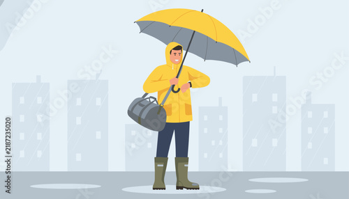 Young man wearing a yellow raincoat and boots holding an umbrella while walking in the rainy city.