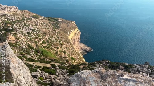Panoramic view from the Dingli Cliffs in Malta, overlooking rugged limestone cliffs and the deep blue Mediterranean Sea. Scenic coastal landscape on a sunny summer day.