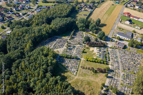Quadro su tela Aerial view of a cemetery with rows of headstones surrounded by green trees