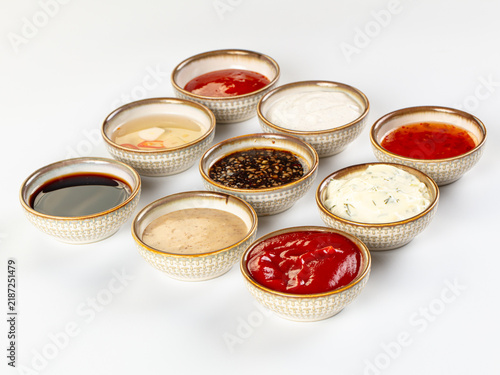 Canvas Print Assorted sauces and condiments in small patterned ceramic bowls on white backgro