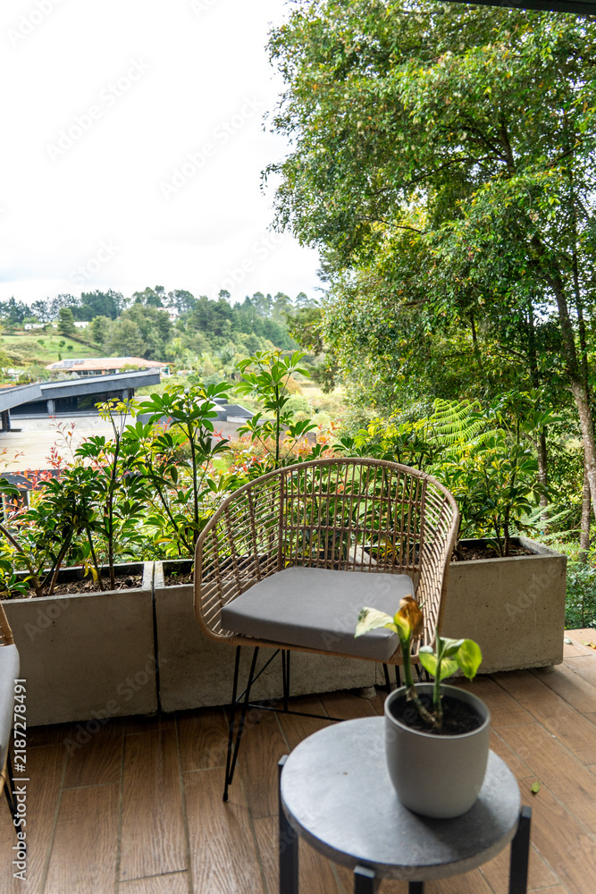 Obraz premium Balcony seating area with wicker chair and potted plants