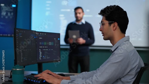 Programmer Typing Code on Dual Monitors in Cyber Security Office