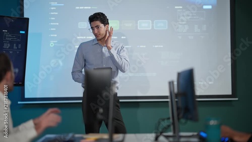 Young Businessman Presenting Data Dashboard on Screen in Modern Office