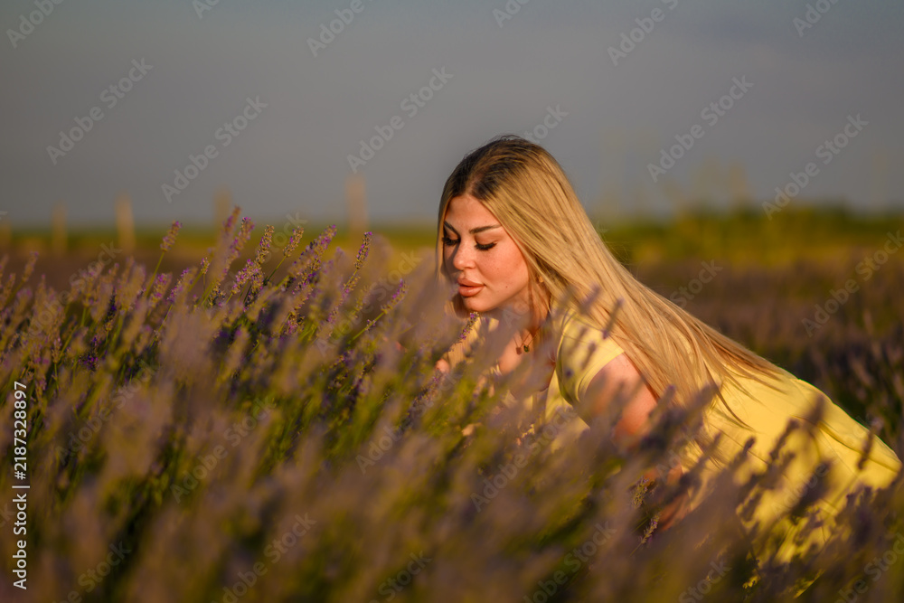 Obraz premium Beautiful young girl posing in lavender field. A bright yellow dress with a soft, flowing fabric set against a background of blooming purple lavender