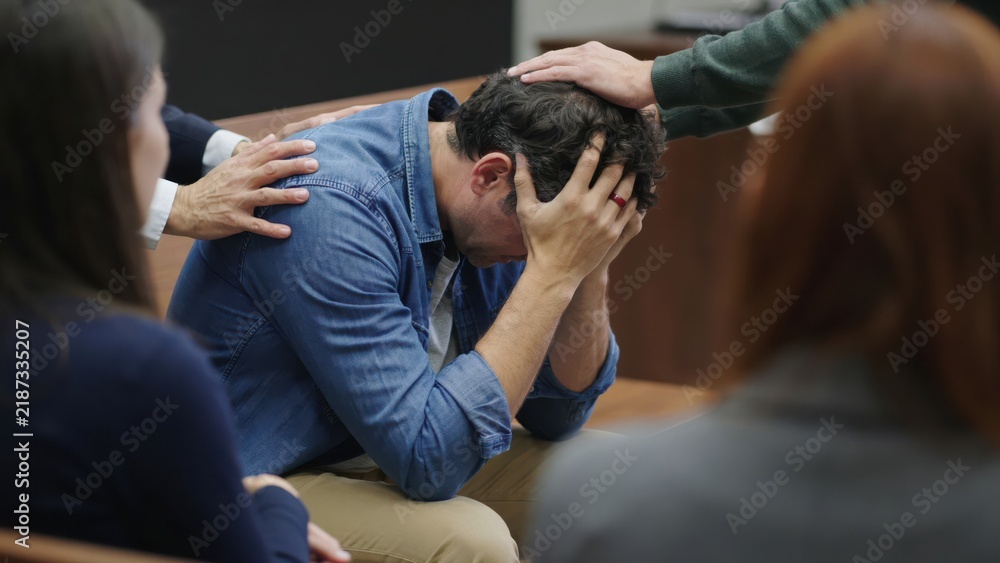 Fototapeta premium Group of people comforting a grieving man