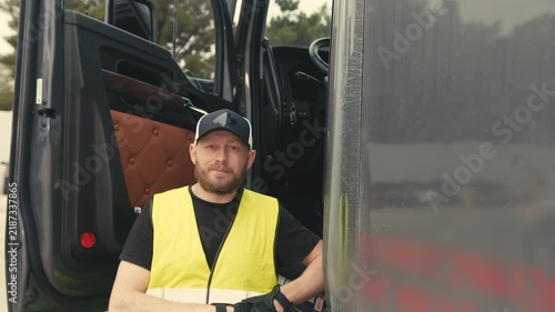 Professional truck driver standing by his semi-truck